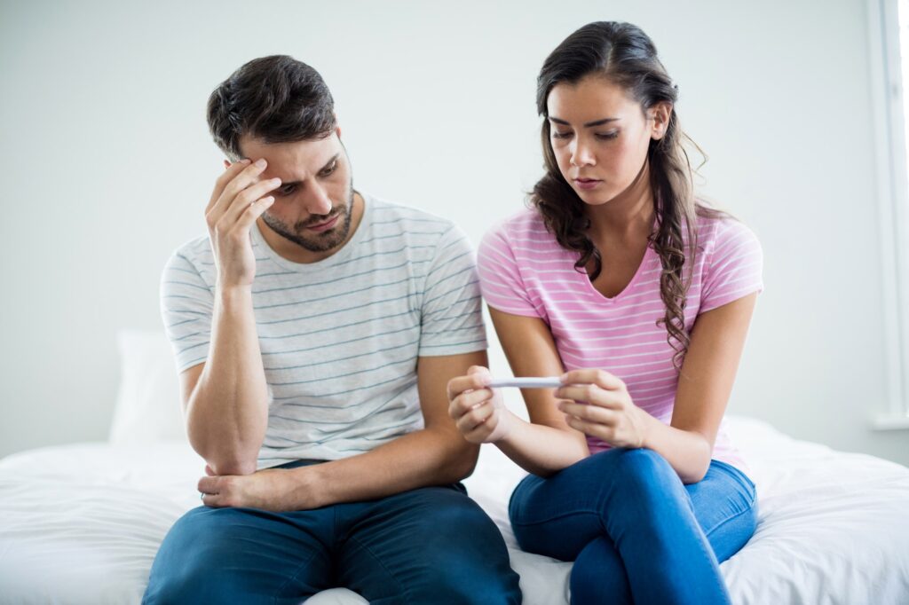 Worried couple finding out results of a pregnancy test in bedroom