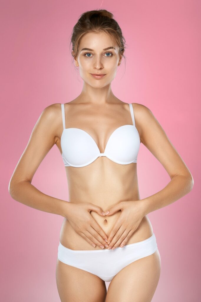 Health issues - female suffering from pain and holding her hands on the stomach